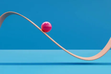 Computer generated image of pink sphere rolling down a plane like a roller coaster.